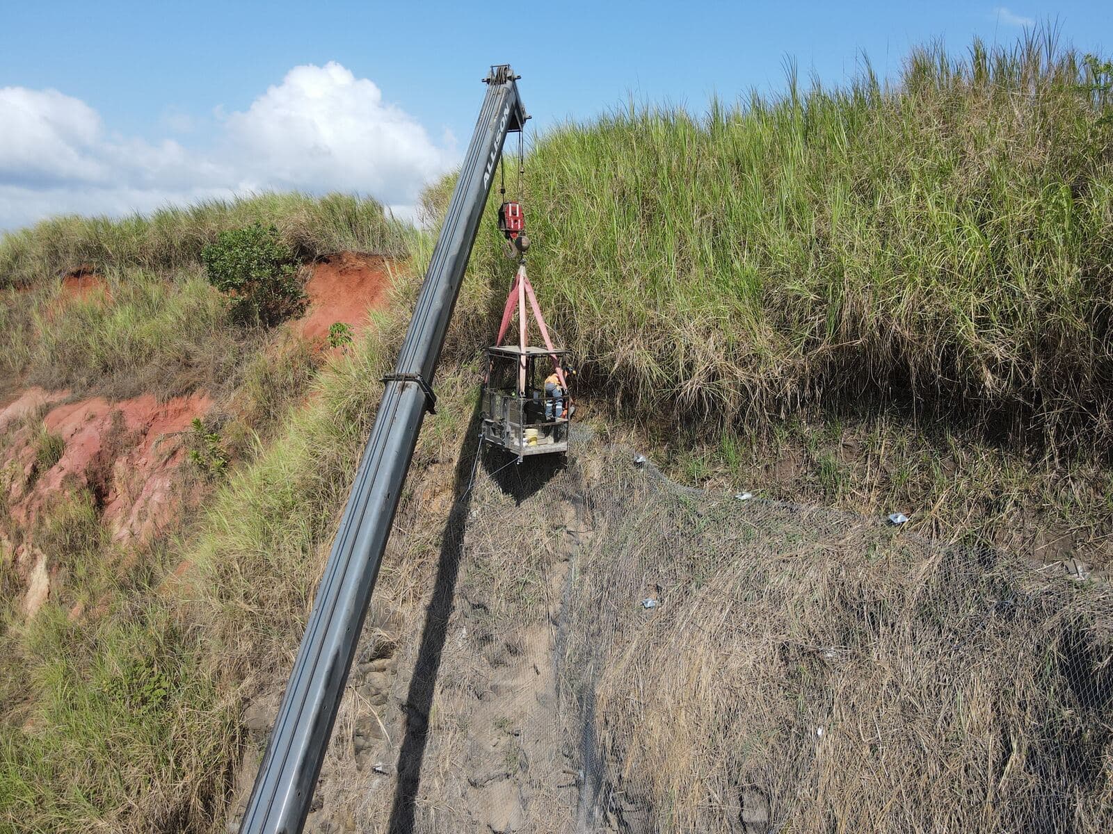 Instalación de malla en talud rocoso desde plataforma suspendida