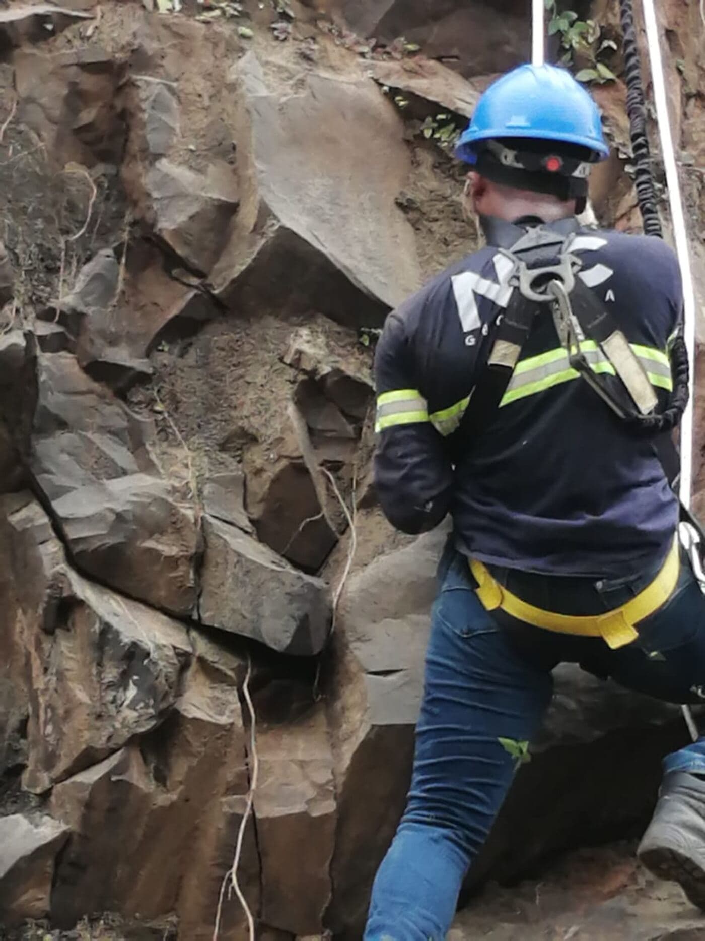 Técnico de NDC Geotecnia en rappel, midiendo discontinuidades sobre el talud rocoso